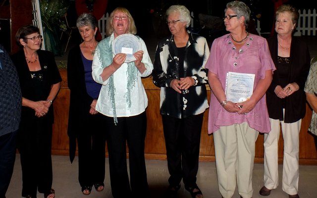 Francia van Dyk (4de van links) staan met die toekenning wat Gansbaai Goue Hande vroeër vanjaar ontvang het en wat tydens die Jaareindfunksie sere-monieel weer aan Gansbaai Goue Hande oorhandig is